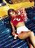 Britney Spears dressed as a cheerleader in red and white, reclining on a blue park bench